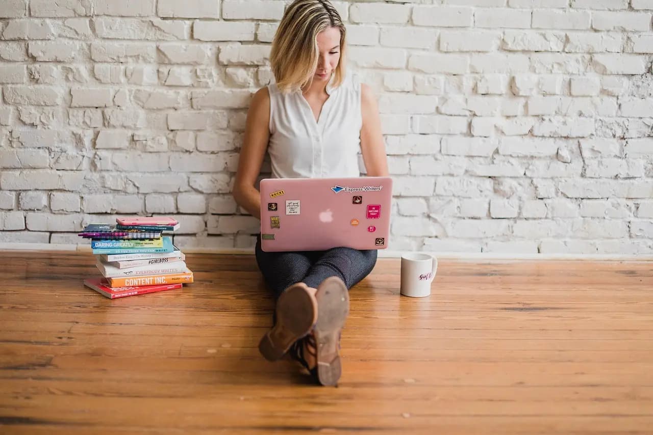 Content creator working on a laptop surrounded by marketing books, representing AI-powered content creation in 1Social