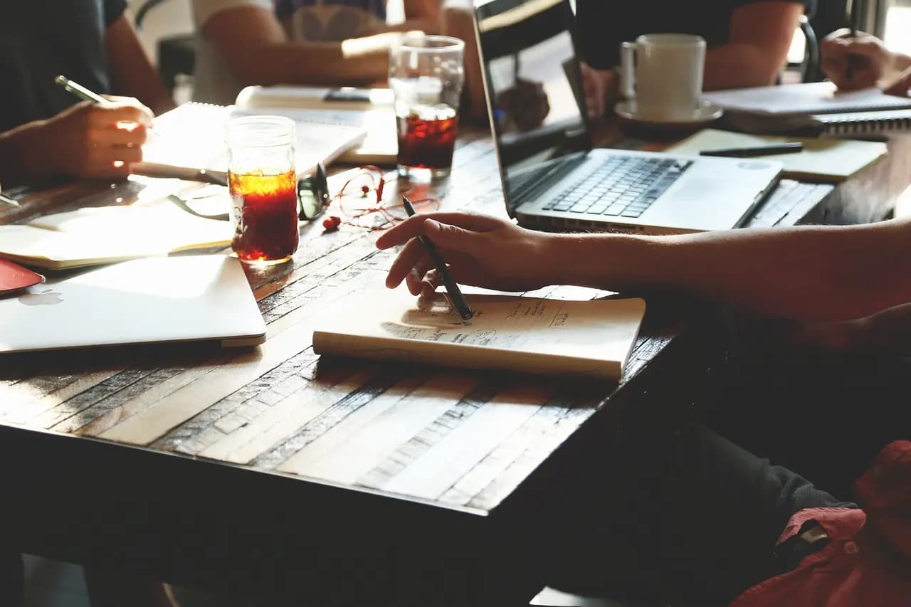 Team of professionals collaborating at a table with laptops and notebooks, representing how agencies use 1Social together